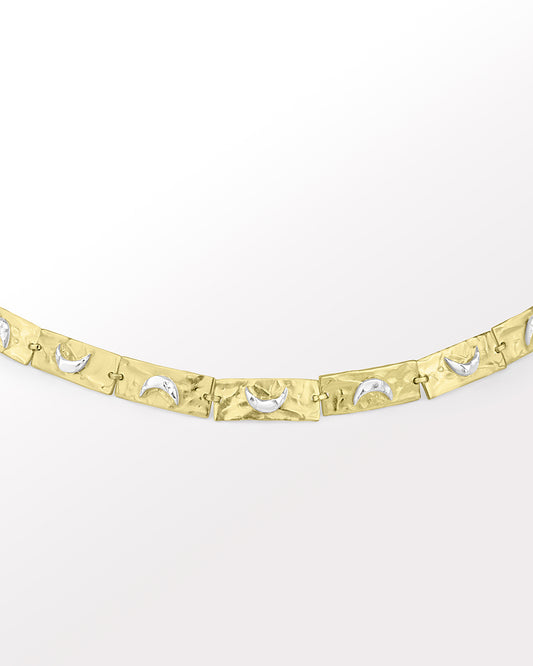 A handcrafted bracelet with a 3D moon crescent charm and a patterned band, with tones of silver and gold.