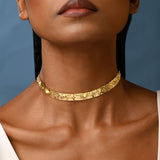Close up of a woman wearing a textured gold choker.