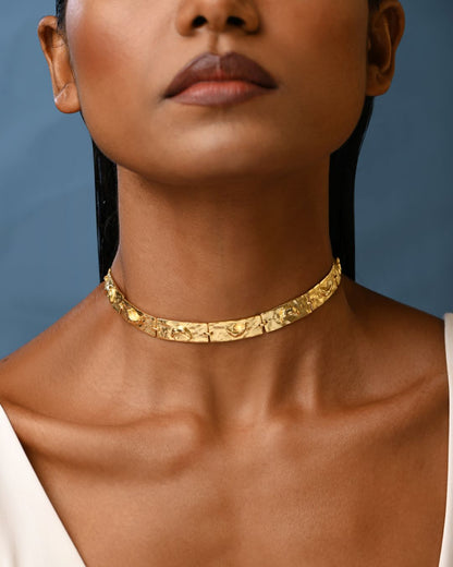 Close up of a woman wearing a textured gold choker.