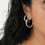 Close-up of a person wearing textured silver hoop earrings